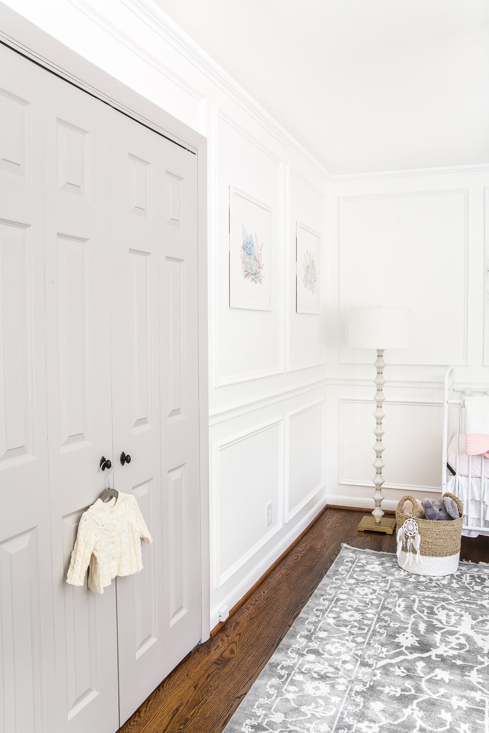 picture frame wall molding in a nursery with white walls and gray doors