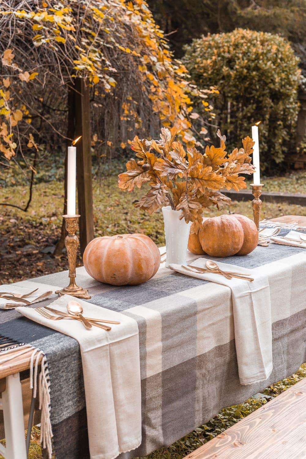 fall branches in a milk glass vase on an outdoor dining table