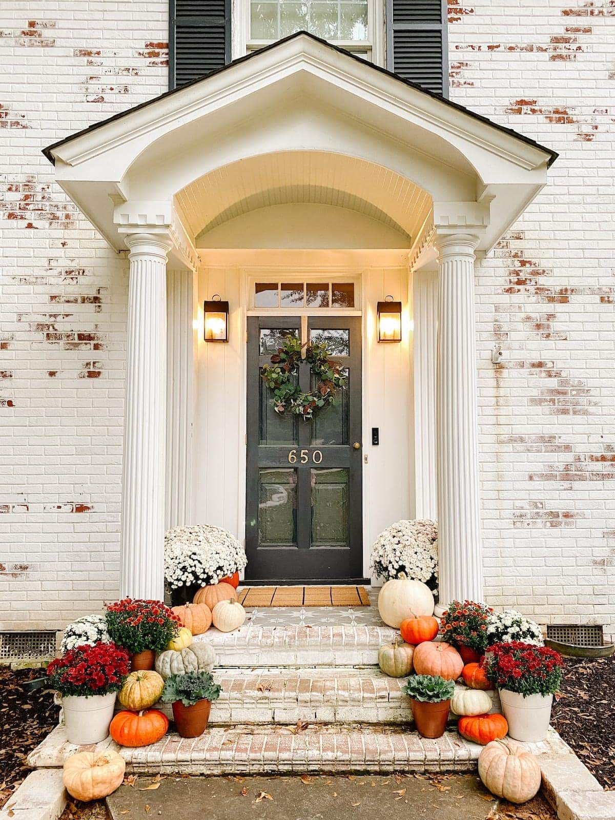 fall porch decor around a front door with real heirloom pumpkins and fall colored mums