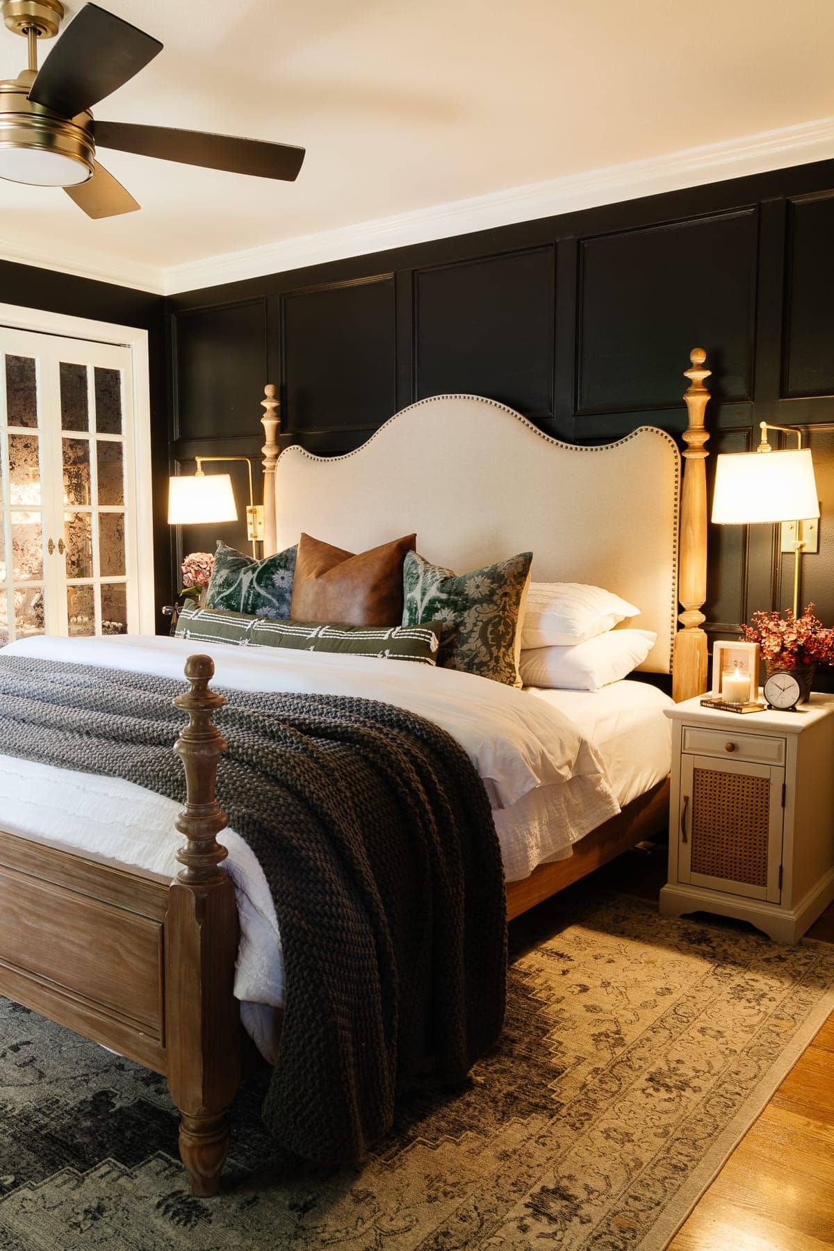 bedroom with black walls and upholstered poster bed