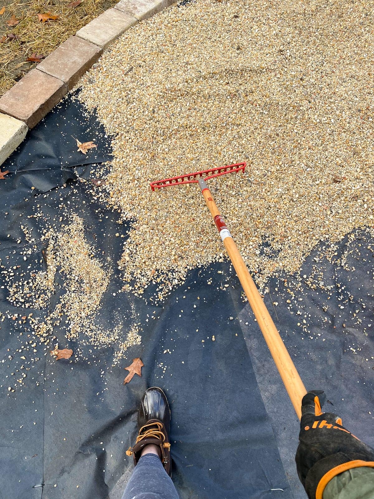 Raking pea gravel on landscape fabric for a fire pit