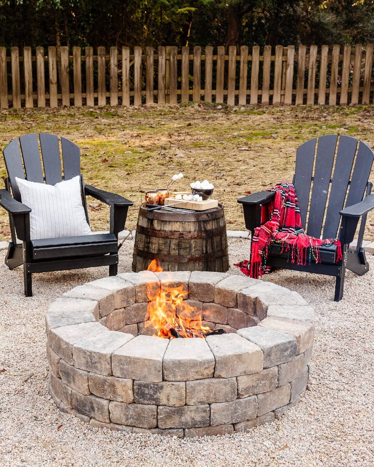 DIY fire pit with stone and pea gravel surrounded by adirondack chairs