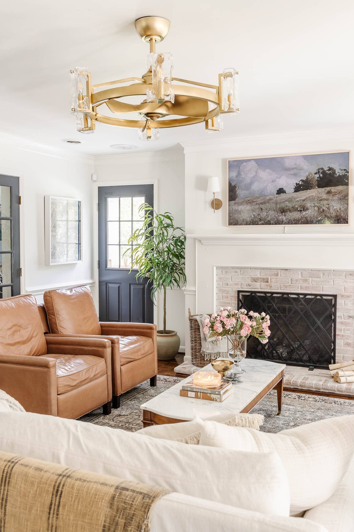 old door in a living room with leather recliners, lime washed brick fireplace, and fandelier
