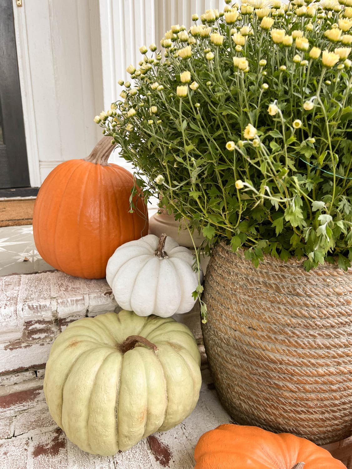 orange, white, and green faux pumpkins with planter of mums